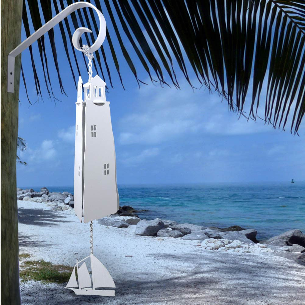 Windchime of a lighthouse with a sailboat on the bottom against an ocean